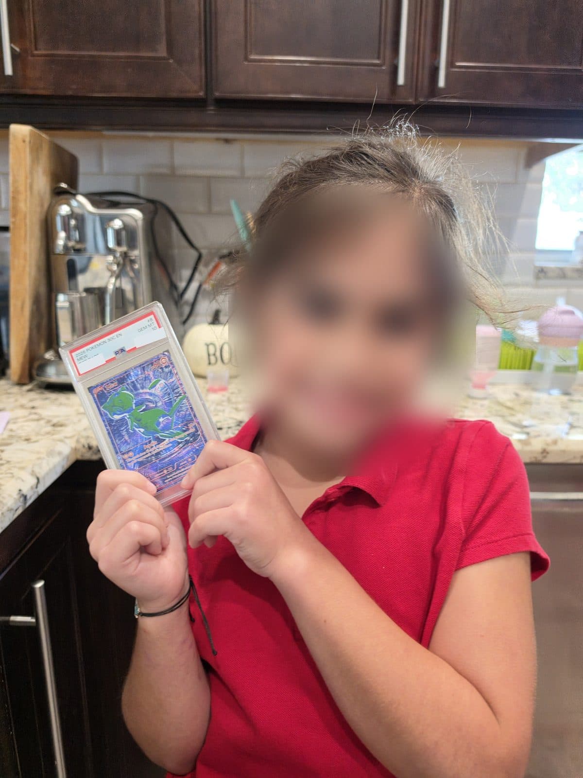 Lila holding the PSA 10 slab up next to her face, her face blurred